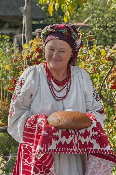 Portrait of old woman in Ukrainian national costume with bread in salt — Stock Photo, Image