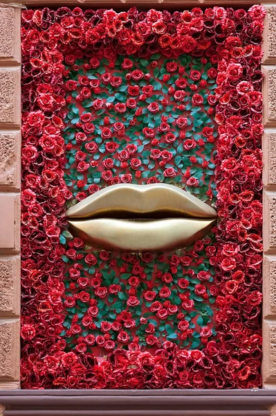 Decoration of bronze lips and paper roses on the wall of a building in Lviv, Ukraine