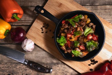 Masanın üzerinde sebzeli demir kızartma tavası.