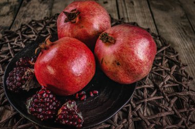 Eski ahşap bir masanın üzerinde nar ve rattan.