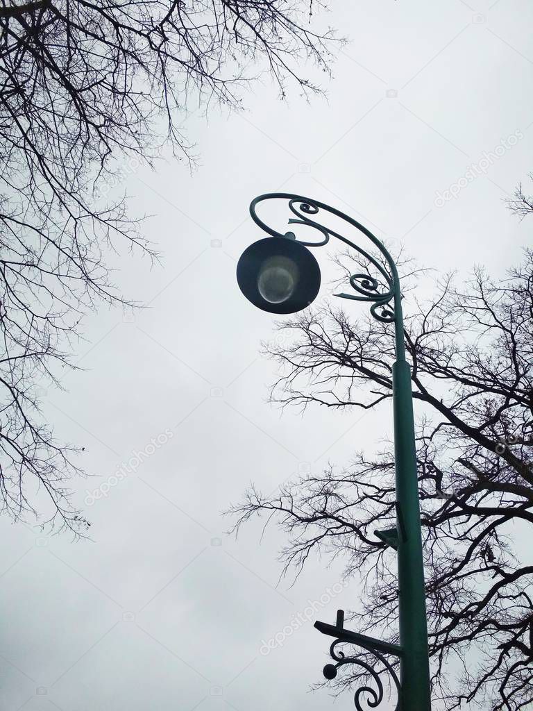 View of an alone streetlight against the background of the cloudy sky on a winter dull day 