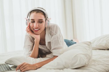 Evde kulaklıkla müzik dinleyen güzel genç bir kadın.