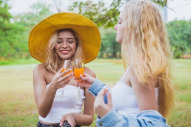 Güzel kız bisiklete bindikten sonra arkadaşlarına sulu bir şeyler ikram eder.