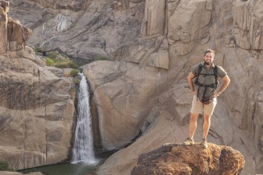Güney Afrika 'daki Augrabies Ulusal Parkı' nda poz veren genç adam. Kameranın önünde gülümsüyor. Yara izi olan bacak. Kaşif