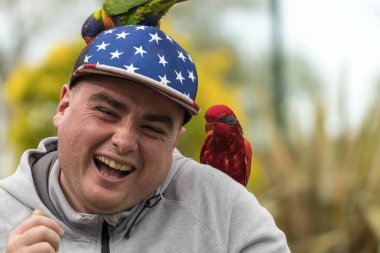 Genç adam hayvanat bahçesinde eğleniyor. Kuşlarla arkadaş olmak. Hayvanlarla gülüyor ve eğleniyoruz..