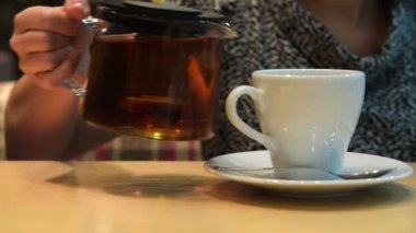 Kafede fincan içine çay dökülen kadın