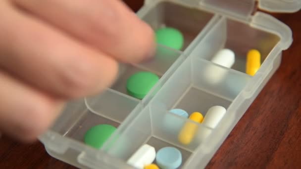 Время, когда женщина кладет лекарства в коробку с таблетками — стоковое видео