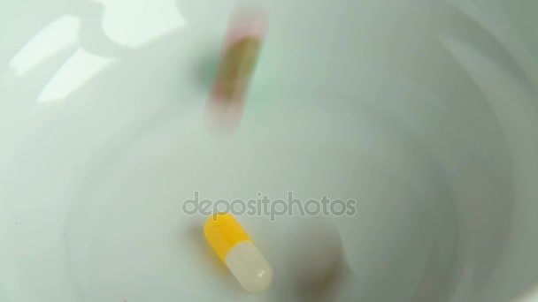 Таблетки падают в миску — стоковое видео
