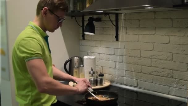 Молодий чоловік готує вечерю на домашній кухні — стокове відео