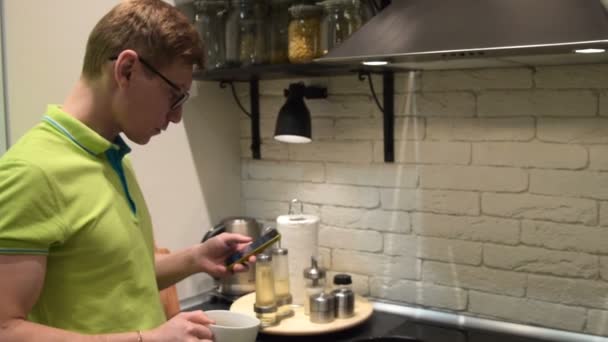Homem usando móvel e beber chá na cozinha — Vídeo de Stock