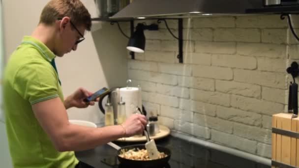 Joven hombre cocinar y navegar por Internet — Vídeo de stock