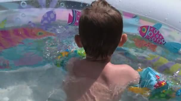 Дитина з водяними крилами купається у відкритому басейні — стокове відео