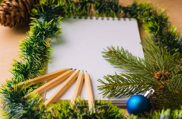 Yeni yıl ve yılbaşı xmas dekorasyon arka planında tahta masasında kalemler olan beyaz bir yer var. 
