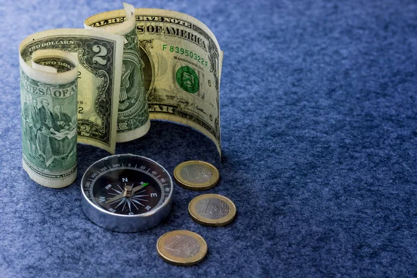 Dolar banknotları ve üzerinde pusula olan avro paraları.