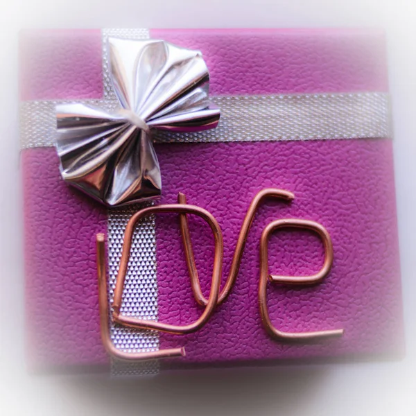 gift box with the inscription love from letters made of copper wire on a white background