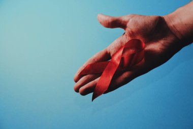 Dünya AIDS Günü 'nde, Ulusal AIDS' te ve yaşlanma aylarında insanların el desteğine kırmızı kurdele takıyor. Mavi arkaplan
