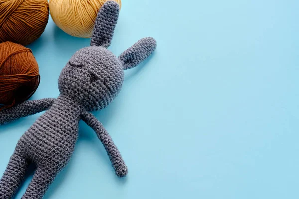 色彩艳丽的纱线在蓝色的背景上用灰色毛绒绒兔清洁. amigurumi玩具制作,手工,针织,玩具娃娃的概念 — 图库照片
