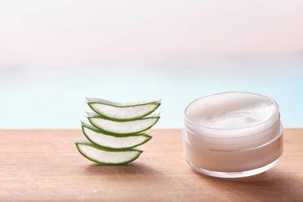 aloe vera dilimleri, bambu kesme yüzeyinde şeffaf krema kutusu, beyaz arka planda izole edilmiş.