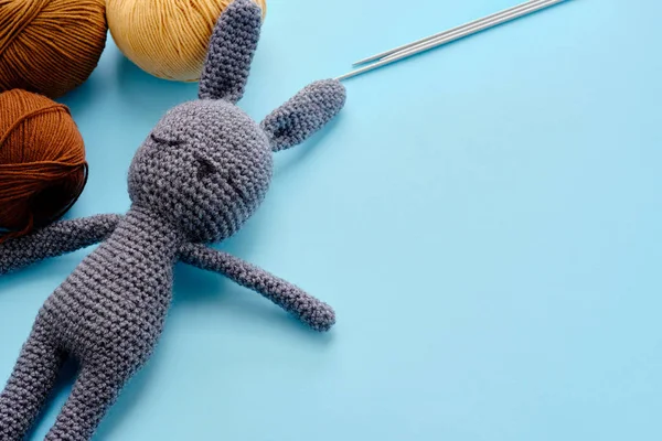 用色彩艳丽的纱线制成的模型，蓝色背景是灰色毛绒兔子。 amigurumi玩具制作,手工,针织,玩具娃娃的概念 — 图库照片