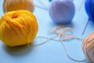 Mavi arkaplanda parlak renk ipliği demetleri. Amigurumi oyuncağı yapma kavramı, el işi, örgü, hobi