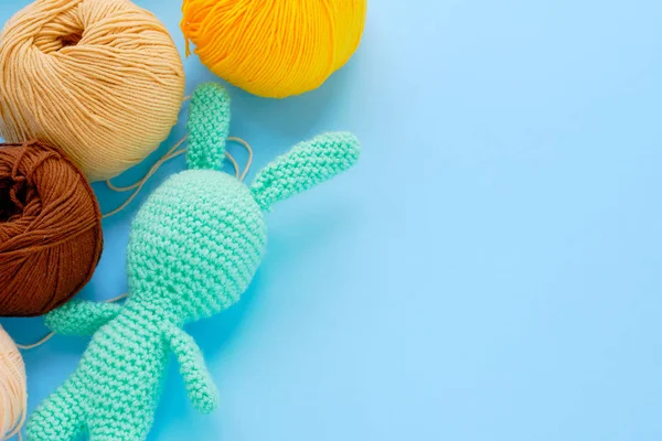 Bright color yarn clews with pastel green stuffed bunny on the blue background. Concept of amigurumi toy making, handcrafting, knitting, hobbie — Stock Photo, Image