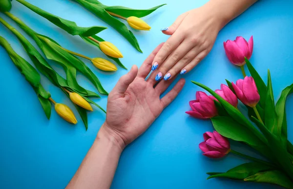 Держаться за руки на синем фоне с тюльпанами, вид сверху, праздничная концепция — стоковое фото