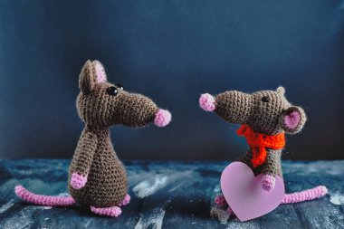El yapımı amigurumi faresi diğerinin karşısında duruyor ve pembe kalp taşıyor. Sevgililer Günü, 14 Şubat, aşk, ilişkiler konsepti.