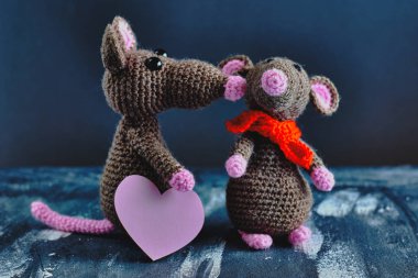 Pembe kalpli el işi amigurumi faresi başka bir oyuncak fareyi öpüyor. Mavi arka plan. Sevgililer Günü, 14 Şubat, aşk, ilişkiler konsepti.