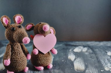 El yapımı amigurumi faresi pembe kalbi hediye olarak tutan başka bir oyuncak farenin yanında duruyor. Sevgililer Günü, 14 Şubat, aşk, ilişkiler konsepti