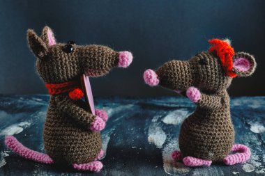 Güzel bir el yapımı amigurumi faresi başka bir oyuncak fareye pembe bir kalp hediye ediyor. Sevgililer Günü, 14 Şubat, aşk, ilişkiler konsepti.