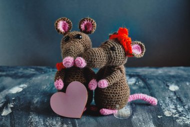 Güzel bir el yapımı amigurumi fare pembe bir kalp tutarken başka bir oyuncak fare sarılıyor. Sevgililer Günü, 14 Şubat, aşk, ilişkiler konsepti.
