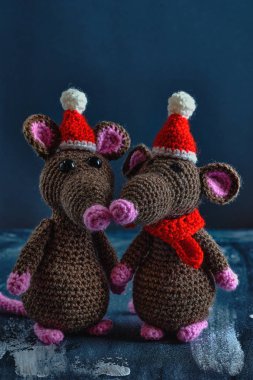 Mavi arka planda duran Noel şapkalı ve kırmızı eşarplı güzel el yapımı amigurumi fareleri. Yeni Yıl 2020 konsepti