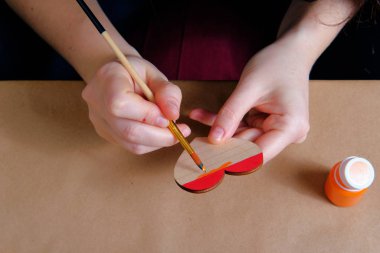 Lgbt gururuyla ahşap kalbi akrilik boyalarla boyayan kadının yan görüntüsü. Sevgililer Günü, usta sınıfı, özel ders, el işi konsepti