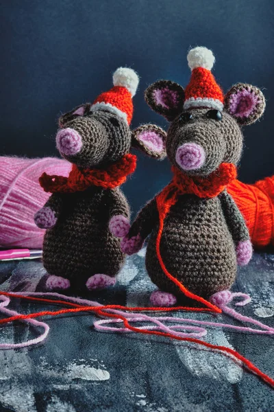 Lovely handcrafted amigurumi rats with christmas hats and red scarves standing near to the bright yarn clews on the blue background. New Year 2020 concept — Stock Photo, Image