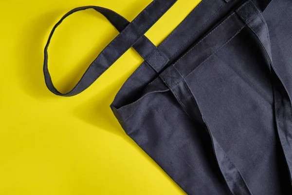 Svart shopper väska gjord med naturliga material på den ljusa gula bakgrunden. Begreppet noll avfall livsstil, ekologi säkerhet, återvunnet avfall, miljöskydd, Earth day. — Stockfoto