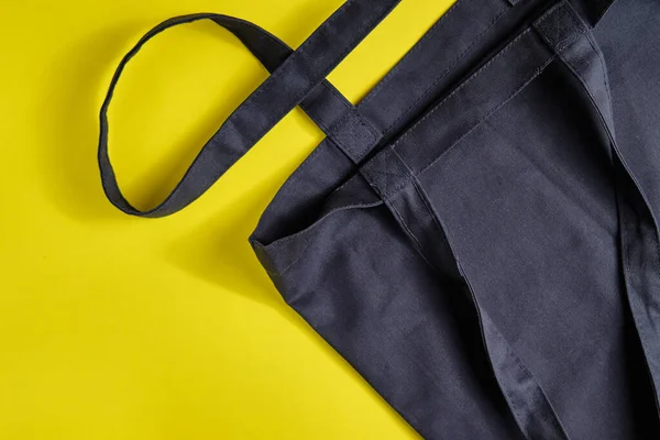 Bolso shopper negro fabricado con materiales naturales sobre fondo amarillo brillante. Concepto de estilo de vida de cero residuos, seguridad ecológica, residuos reciclados, protección del medio ambiente, día de la Tierra . —  Fotos de Stock