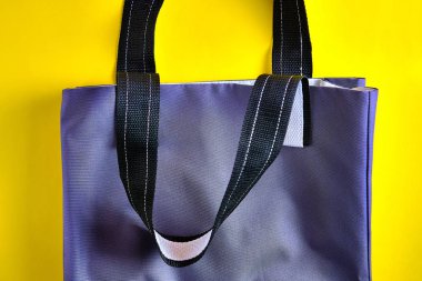 Parlak sarı arka planda doğal malzemelerle yapılmış gri tekstil çantasının yan görüntüsü. Sıfır atık yaşam tarzı kavramı, çevre koruma, Dünya günü.