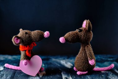 El yapımı amigurumi faresi diğerinin karşısında duruyor ve pembe kalp taşıyor. Sevgililer Günü, 14 Şubat, aşk, ilişkiler konsepti