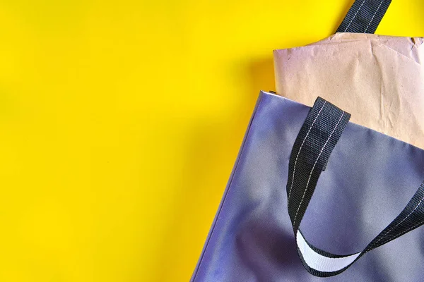 Bolsa de mano gris hecha con materiales naturales con paquete de papel sobre el fondo amarillo brillante. Concepto de estilo de vida de cero residuos, protección del medio ambiente, Día de la Tierra . —  Fotos de Stock
