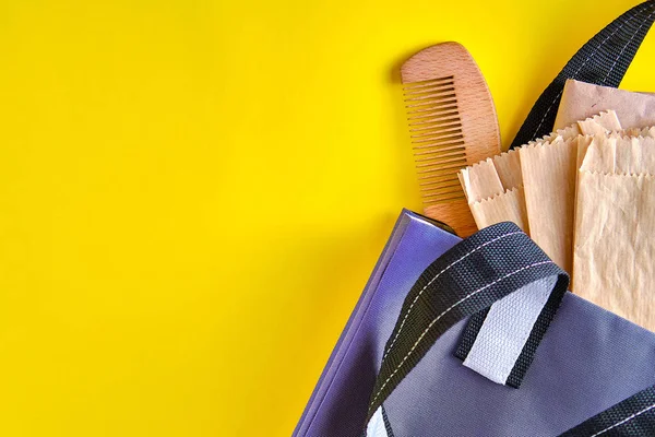 Doğal malzemelerle yeniden kullanılabilir kağıt paketler ve içinde ahşap tarakla yapılmış bir çanta. Sıfır atık yaşam tarzı kavramı, çevre koruma, Dünya günü.