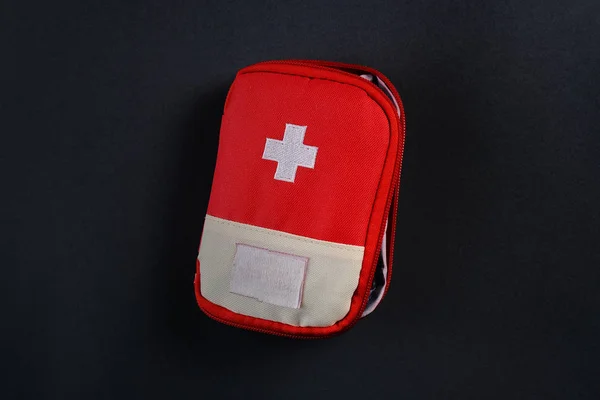 Closed red travel first aid kit pouch on the dark background. Photo with a copy space — Stock Photo, Image