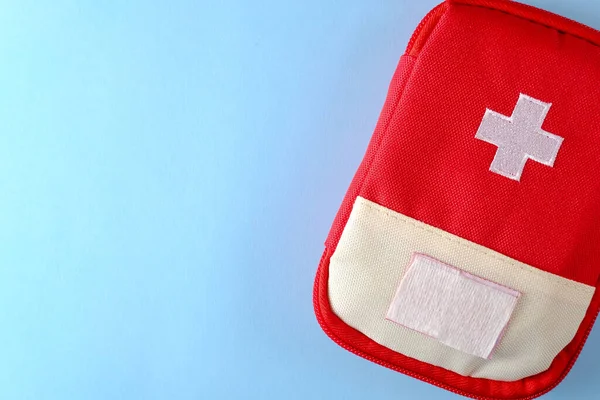 Closed red travel first aid kit pouch on the bright blue background. Photo with a copy space