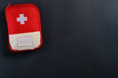 Koyu arka planda kapalı kırmızı seyahat ilk yardım çantası. Kopyalama alanı olan fotoğraf