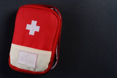 Koyu arka planda kapalı kırmızı seyahat ilk yardım çantası. Kopyalama alanı olan fotoğraf