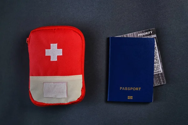 Kék külső útlevél repülőjegy belsejében és piros utazási elsősegély csomag tasak a sötét háttér — Stock Fotó