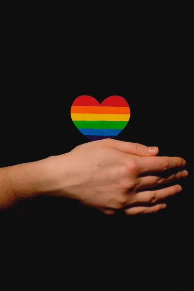 Koyu arkaplanda Lgbt gururu renginde kalbi tutan kadın kolları. Uluslararası Homofobi Günü kavramı, cinsel eşitlik, feminizm, sosyal güvenlik ve korunma — Stok fotoğraf