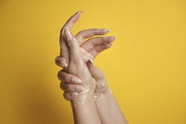 Sarı arka planda sabunlu kadın eli