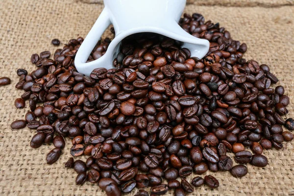 Kávová zrna a šálek na pytel módních podmínek. — Stock fotografie