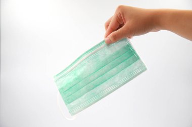 Yeşil desenli masa arkasında cerrahi koruyucu antiviral maske tutan bir kadın. Virüsü yaymak için koruyucu. Corona virüsü konsepti COVID-19 karantina salgın risk bölgesi.