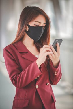 Maske takan ve cep telefonuyla konuşan Asyalı bir kadın PM2.5 'u korumak ve Covid-19 virüsü salgını yüzünden öksürüp duruyor..